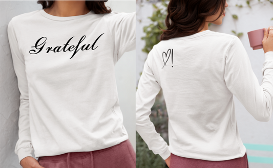 On the front of this custom long sleeve t-shirt in cursive writing is the word grateful on the upper chest, on the back left shoulder blade is an image of a heart with an exclamation mark next to it.