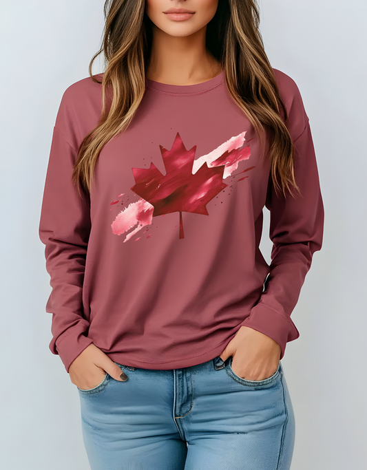 On the front of this unisex long sleeve shirt is an image of a Canadian maple leaf that is bright red, it looks like it has been spray painted onto the front of the shirt.
