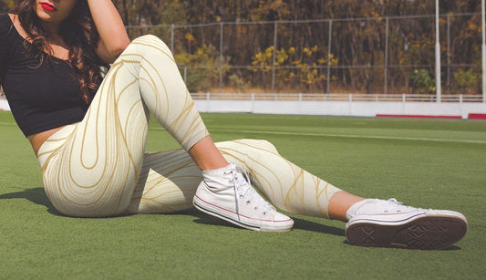 These custom women's high waisted leggings have a base color of a light beige that fades to a even brighter beige at points to give off a 3D wave design, there are gold lines overlayed across the top of the beige that contour to the body.