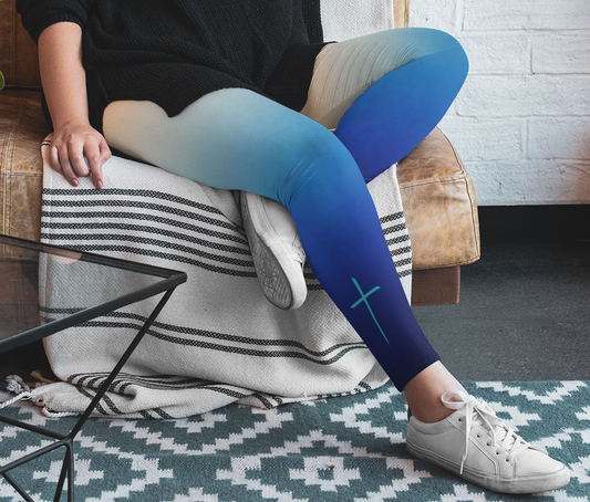 A pair custom handmade high waisted women's ombre leggings, the top of the leggings starts as a orange then it fades to a light blue then to a turquoise blue then finally a navy blue at the ankle, there is a turquoise blue Jesus cross on the right calf of the pant.