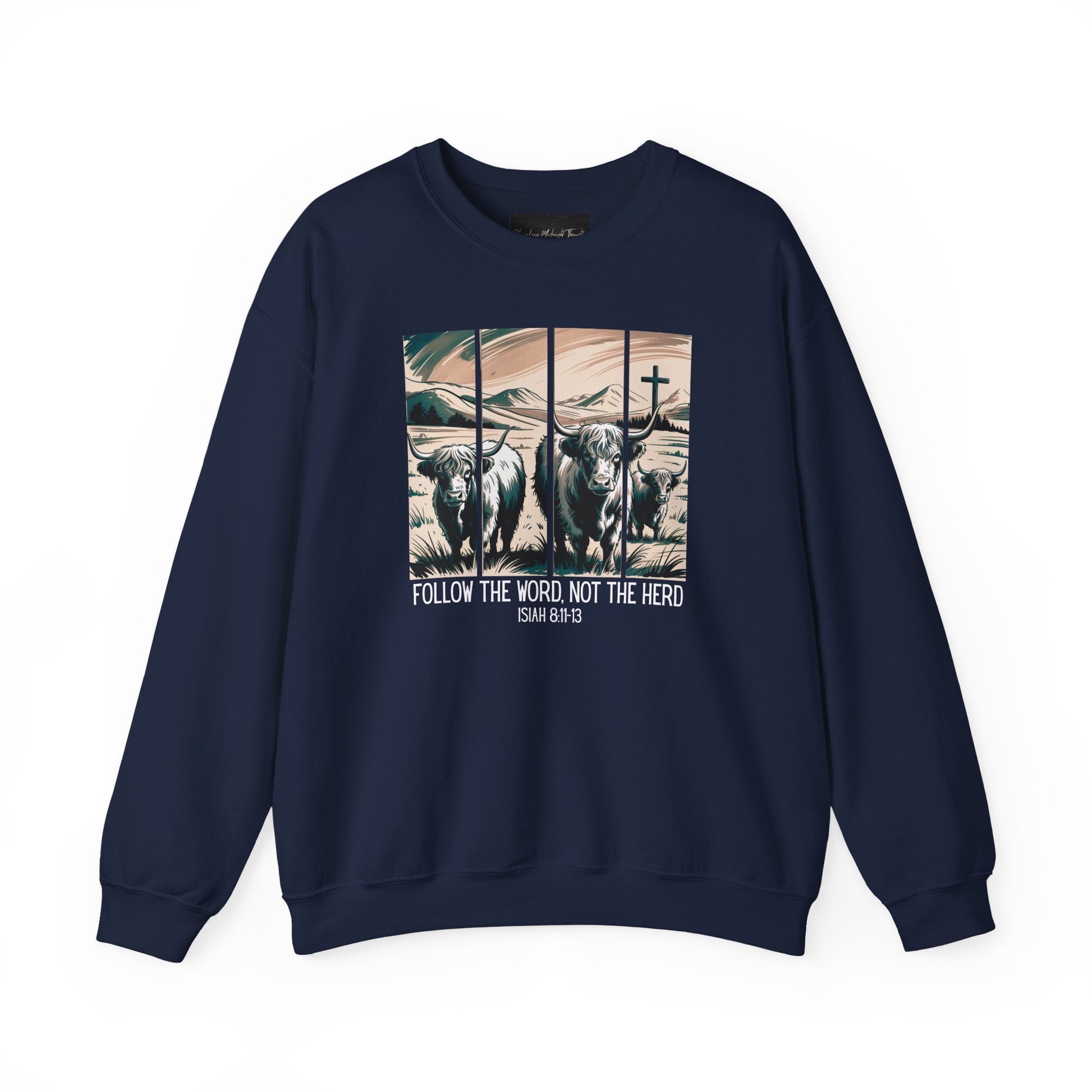 On the front of this Christian pullover sweatshirt is the image of cows standing in a pasture that is in a valley surrounded by mountains, there is a Jesus cross behind the cows, underneath the image is the scripture Follow the word, not the herd Isiah 8:11-13