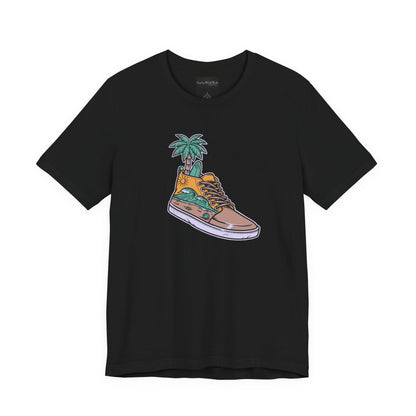 On the front of this custom handmade short sleeve shirt is an image of a high top running shoe with ocean waves running along the side of the shoe, coming out of the top of the shoe where your foot goes is a palm tree and a surf board.