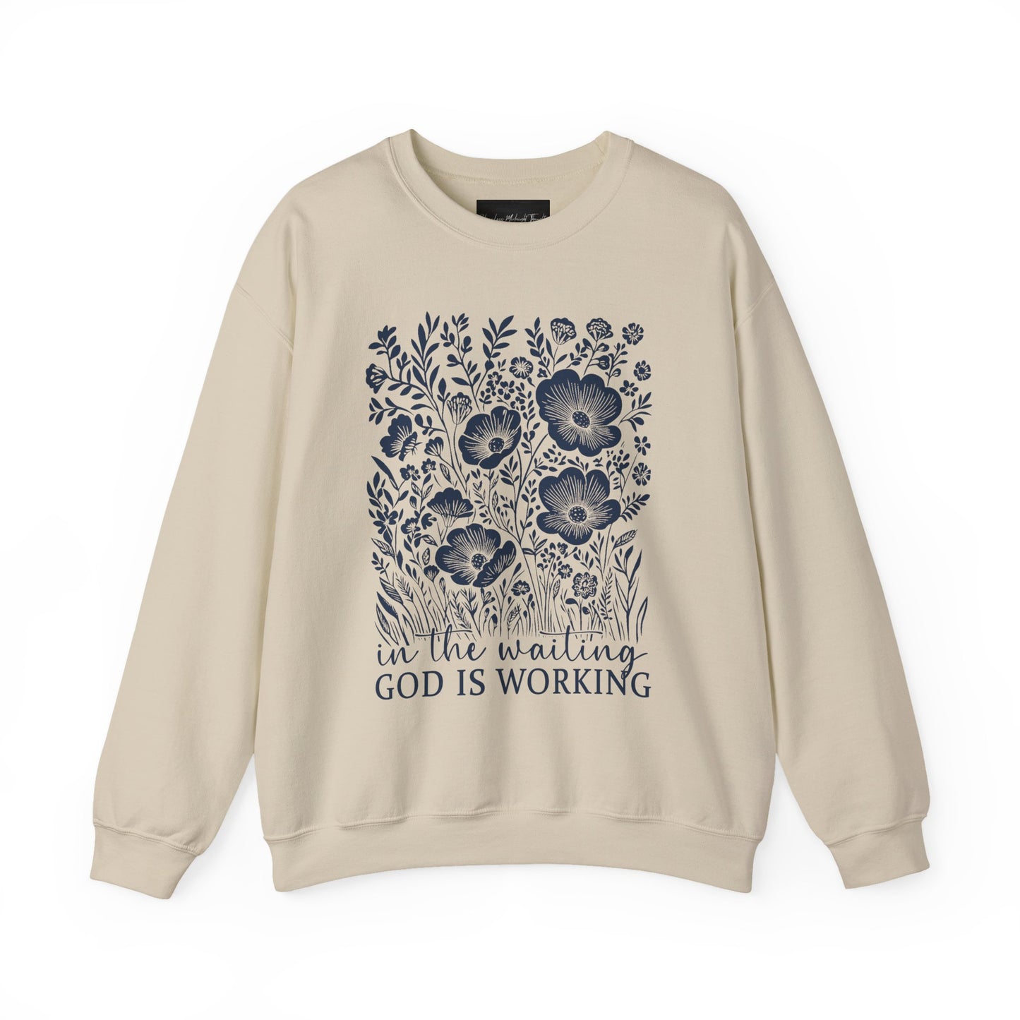 On the front of this custom women's Christian pullover sweatshirt are a bunch of wildflowers with the words in the waiting God is working underneath the flowers.