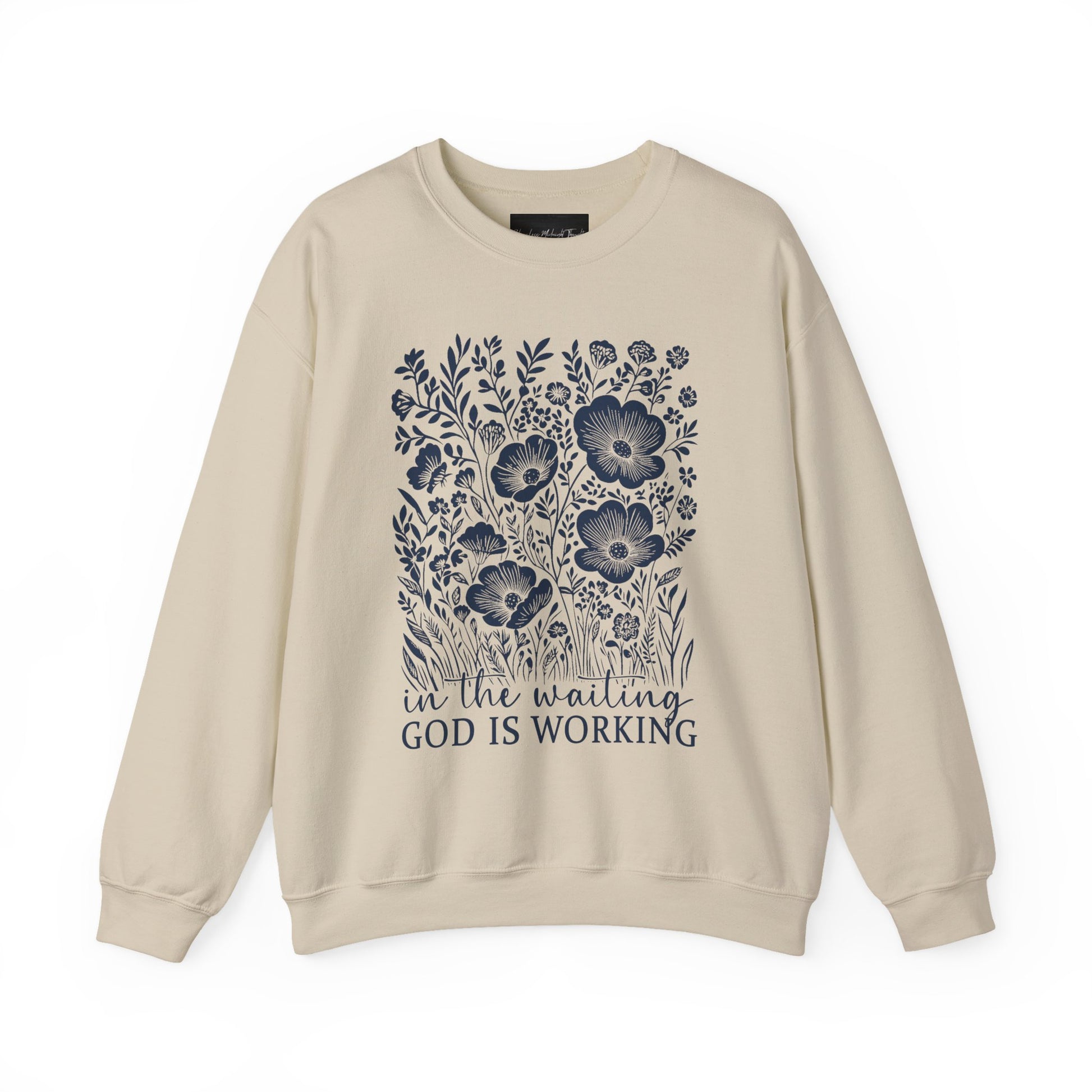 On the front of this custom women's Christian pullover sweatshirt are a bunch of wildflowers with the words in the waiting God is working underneath the flowers.