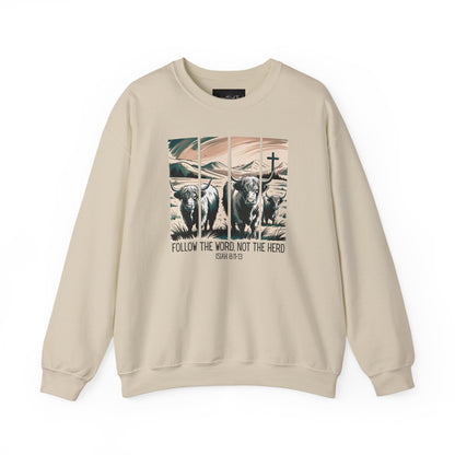 On the front of this Christian pullover sweatshirt is the image of cows standing in a pasture that is in a valley surrounded by mountains, there is a Jesus cross behind the cows, underneath the image is the scripture Follow the word, not the herd Isiah 8:11-13