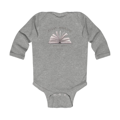 On the front of this custom baby onesie are the words First Edition Published 2026 with an image of an open book in the middle of the wording.