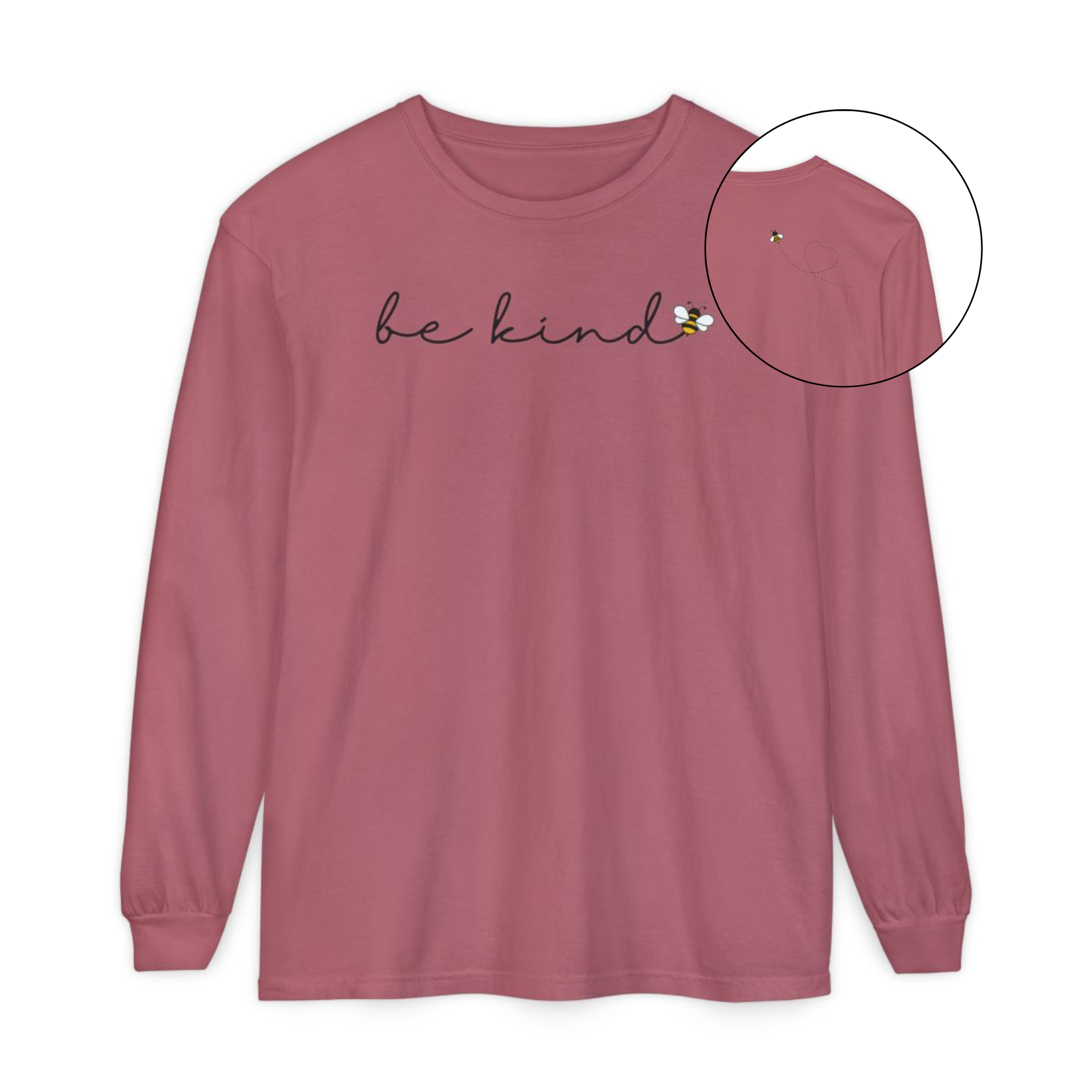 On the front of this custom unisex long sleeve shirt are the words be kind in a simple cursive font, with a bumble bee on the right side of the letter kind, on the back right shoulder there is an image of a bumble bee flying and leaving a trail behind it in the shape of a heart.