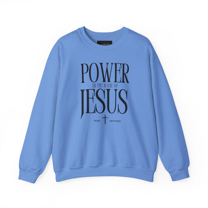 On the front of this Christian pullover sweatshirt it says Power In The Name Of Jesus with a Jesus cross underneath it, on either side of the cross are the words Fear and Nothing.