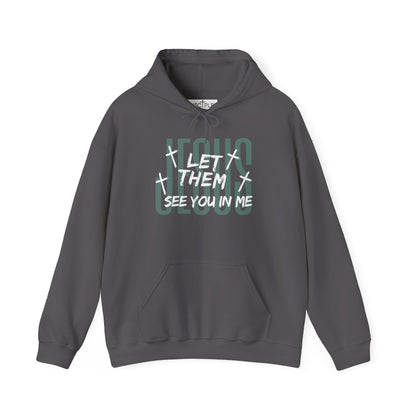 On the front of this custom Christian hoodie it says Jesus in large letters with the words Let them see you in me overlayed overtop of Jesus, there are crosses around the wording.