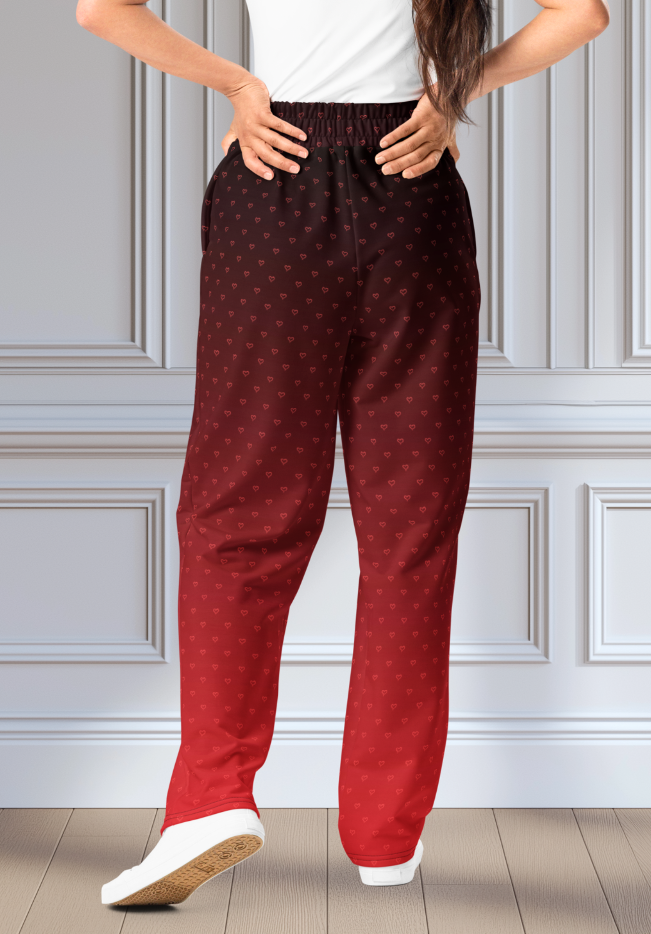 A pair of wide leg ombre sweatpants with the top of the sweats being black and then it fading to a bright red at the bottom of the pants, there are a bunch of red hearts overlayed on the top that then blend into the same shade of red at the bottom of the sweats.