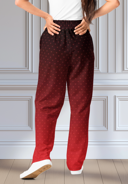 A pair of wide leg ombre sweatpants with the top of the sweats being black and then it fading to a bright red at the bottom of the pants, there are a bunch of red hearts overlayed on the top that then blend into the same shade of red at the bottom of the sweats.