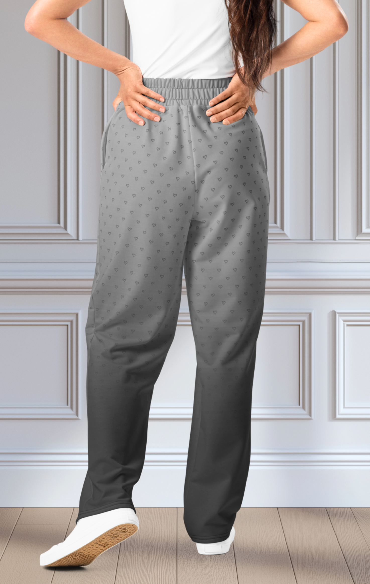 A pair of custom wide leg ombre sweatpants starting off as a light grey at the top then fading to a dark slate at the bottom, there is a dark slate grey heart pattern overlayed on the top that fades into the bottom of the sweatpants.