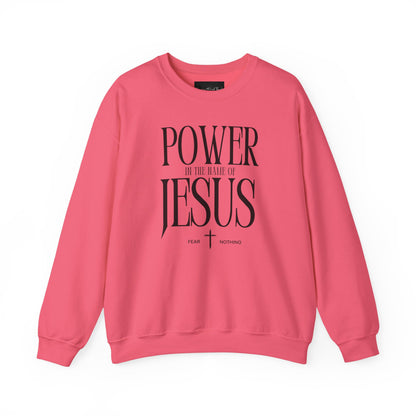 On the front of this Christian pullover sweatshirt it says Power In The Name Of Jesus with a Jesus cross underneath it, on either side of the cross are the words Fear and Nothing.