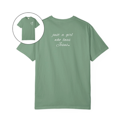 On the front of this custom women's Christian t-shirt is a heart with a cross through it, on the back top of the shirt right between the shoulder blades are the words just a girl who loves Jesus in a cursive writing.