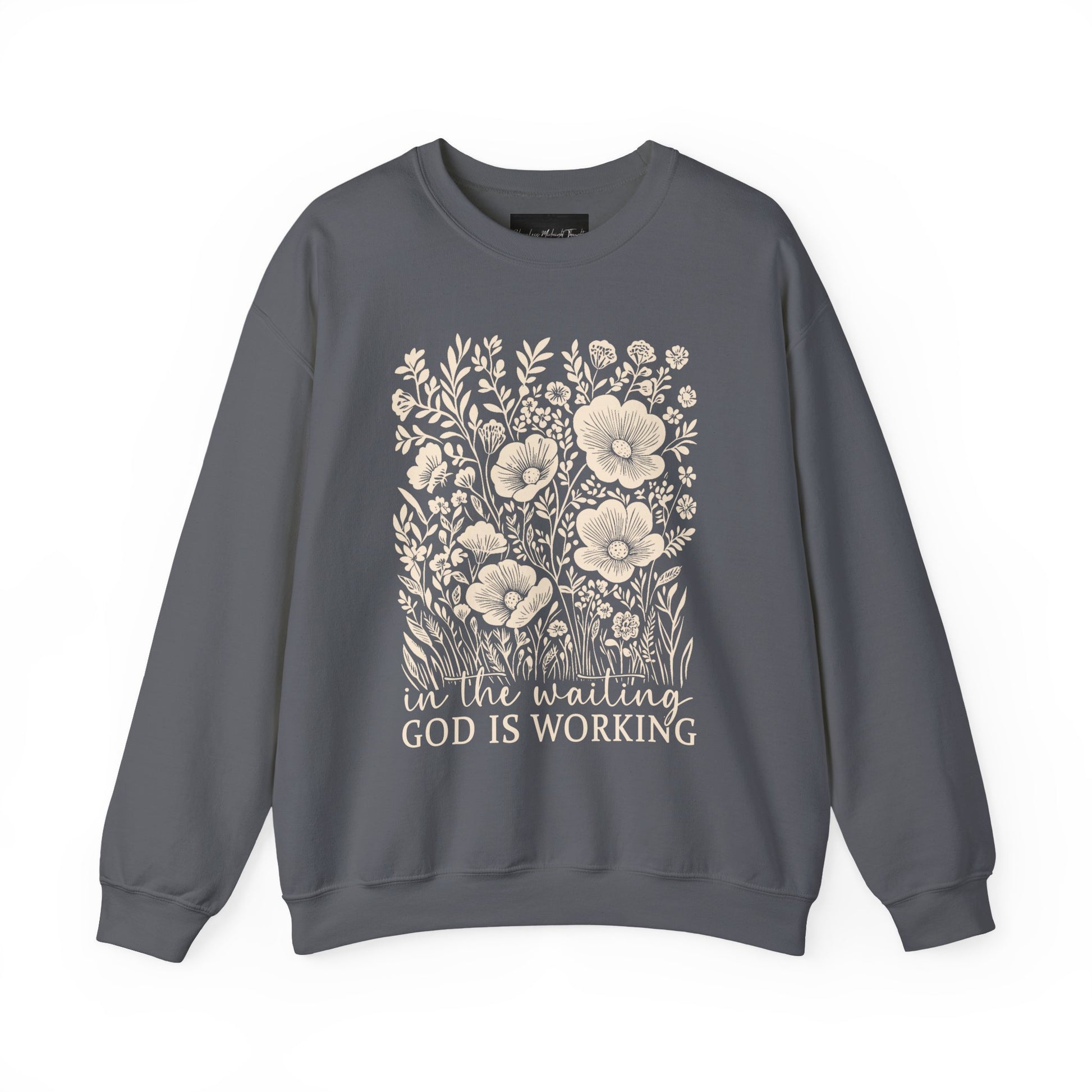 On the front of this custom women's Christian pullover sweatshirt are a bunch of wildflowers with the words in the waiting God is working underneath the flowers.