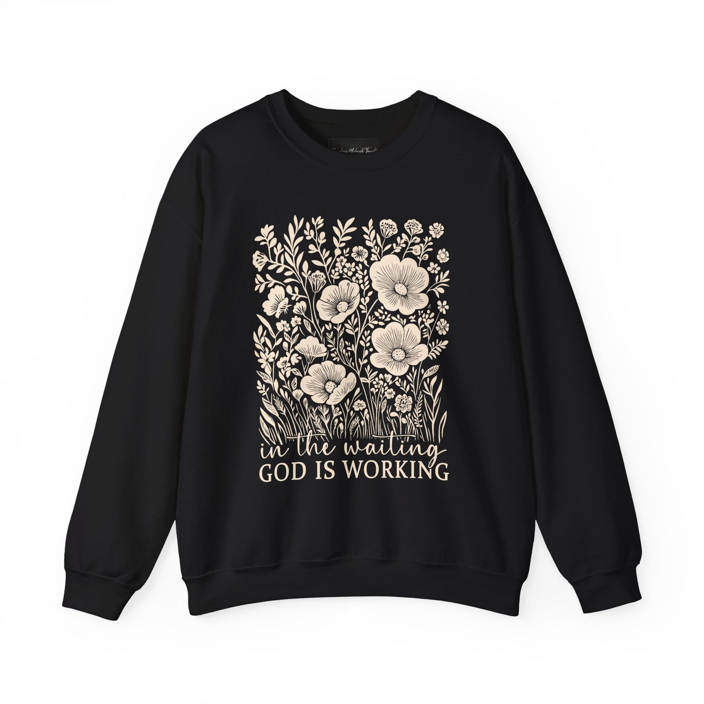 On the front of this custom women's Christian pullover sweatshirt are a bunch of wildflowers with the words in the waiting God is working underneath the flowers.