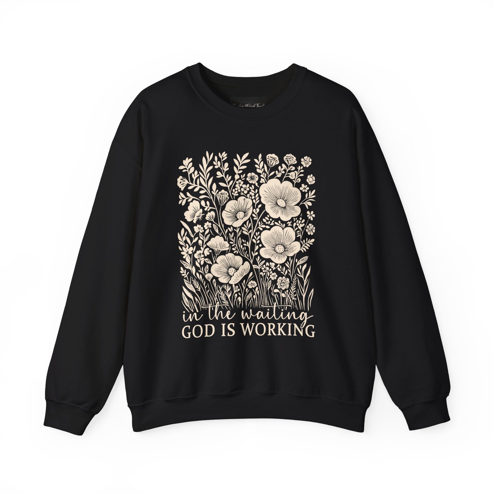 On the front of this custom women's Christian pullover sweatshirt are a bunch of wildflowers with the words in the waiting God is working underneath the flowers.