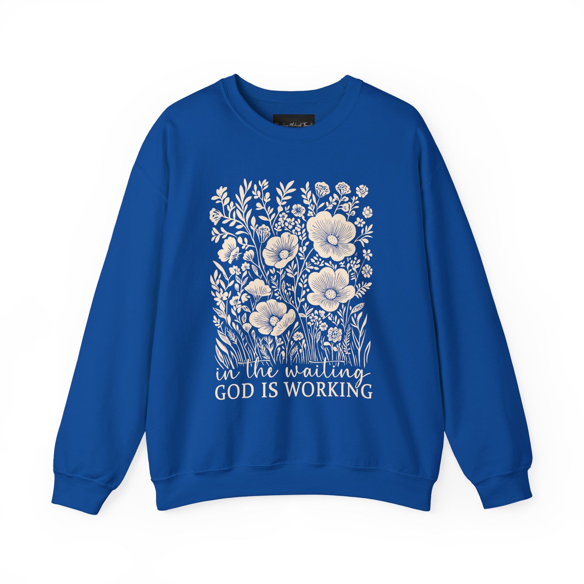 On the front of this custom women's Christian pullover sweatshirt are a bunch of wildflowers with the words in the waiting God is working underneath the flowers.