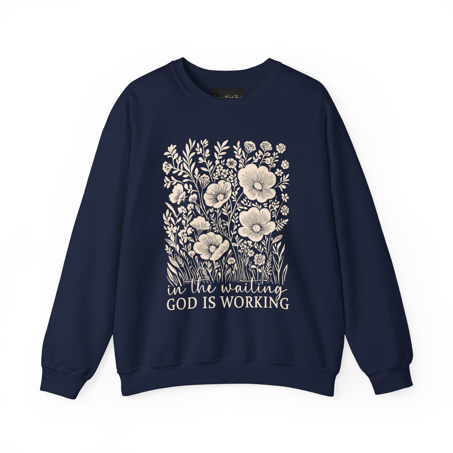 On the front of this custom women's Christian pullover sweatshirt are a bunch of wildflowers with the words in the waiting God is working underneath the flowers.