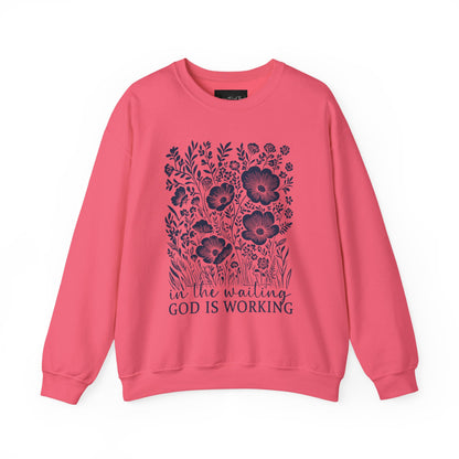 On the front of this custom women's Christian pullover sweatshirt are a bunch of wildflowers with the words in the waiting God is working underneath the flowers.