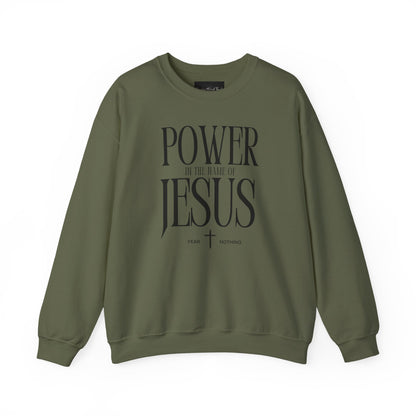 On the front of this Christian pullover sweatshirt it says Power In The Name Of Jesus with a Jesus cross underneath it, on either side of the cross are the words Fear and Nothing.