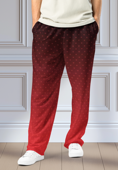 A pair of wide leg ombre sweatpants with the top of the sweats being black and then it fading to a bright red at the bottom of the pants, there are a bunch of red hearts overlayed on the top that then blend into the same shade of red at the bottom of the sweats.