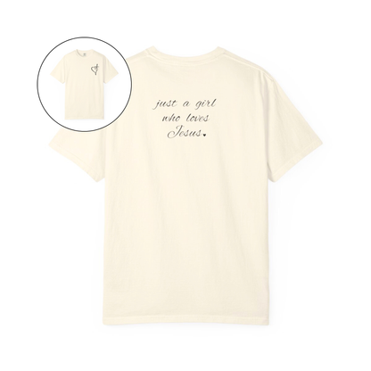 On the front of this custom women's Christian t-shirt is a heart with a cross through it, on the back top of the shirt right between the shoulder blades are the words just a girl who loves Jesus in a cursive writing.