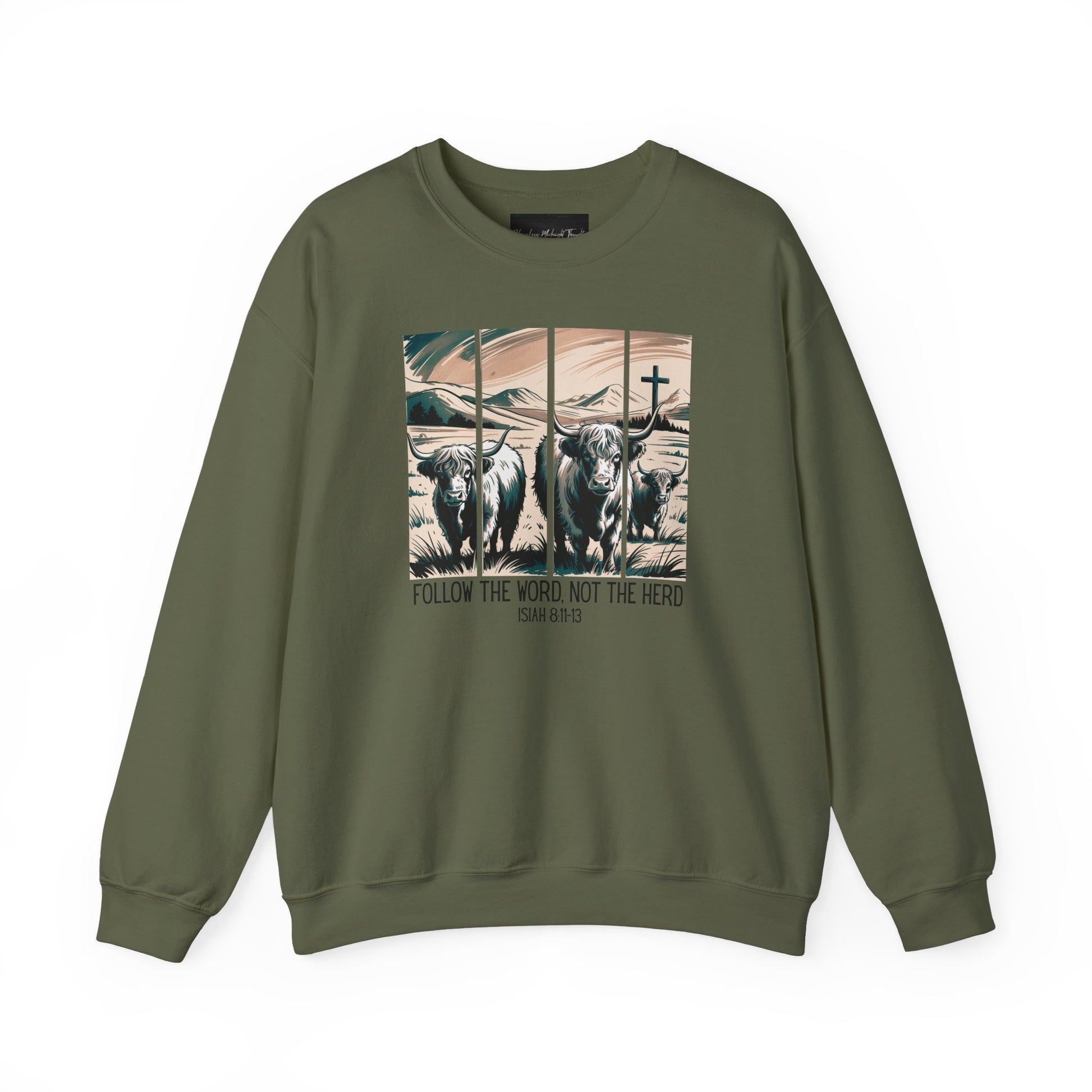 On the front of this Christian pullover sweatshirt is the image of cows standing in a pasture that is in a valley surrounded by mountains, there is a Jesus cross behind the cows, underneath the image is the scripture Follow the word, not the herd Isiah 8:11-13