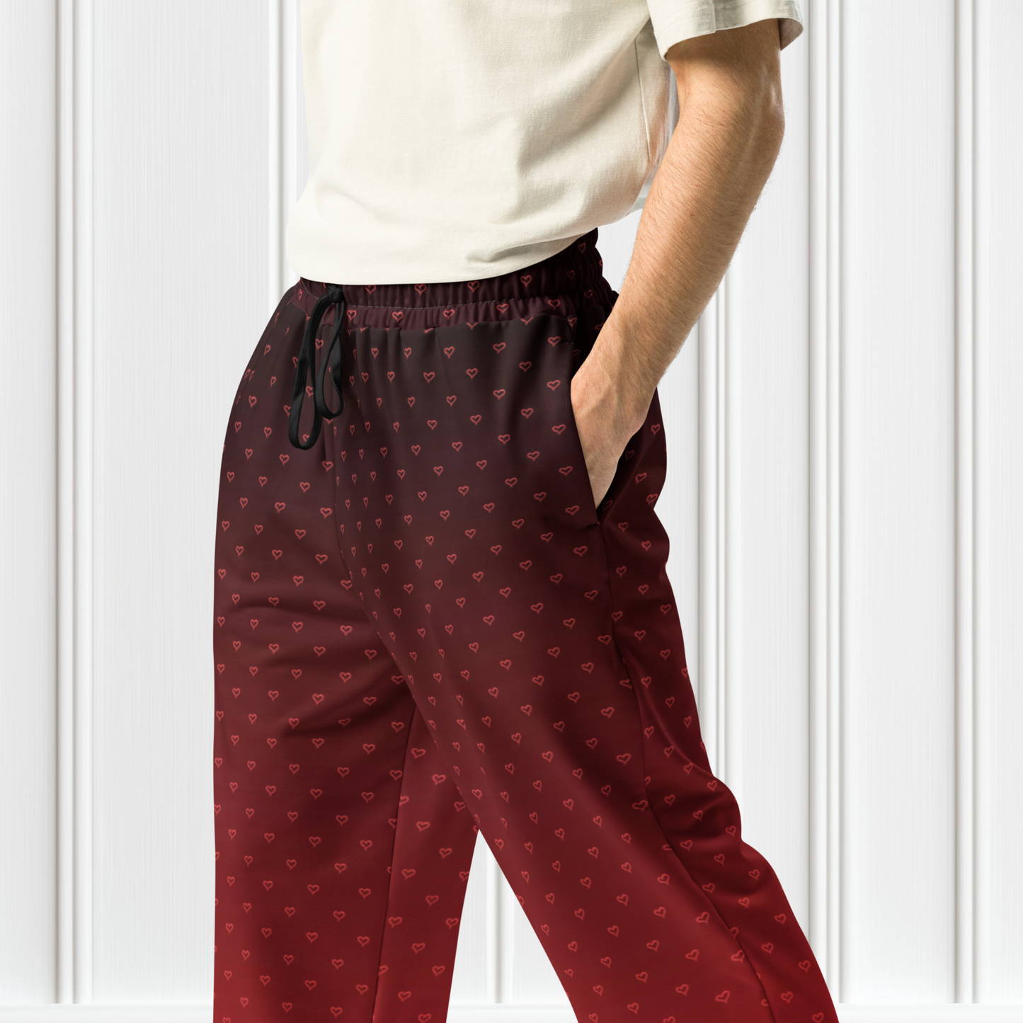 A pair of wide leg ombre sweatpants with the top of the sweats being black and then it fading to a bright red at the bottom of the pants, there are a bunch of red hearts overlayed on the top that then blend into the same shade of red at the bottom of the sweats.