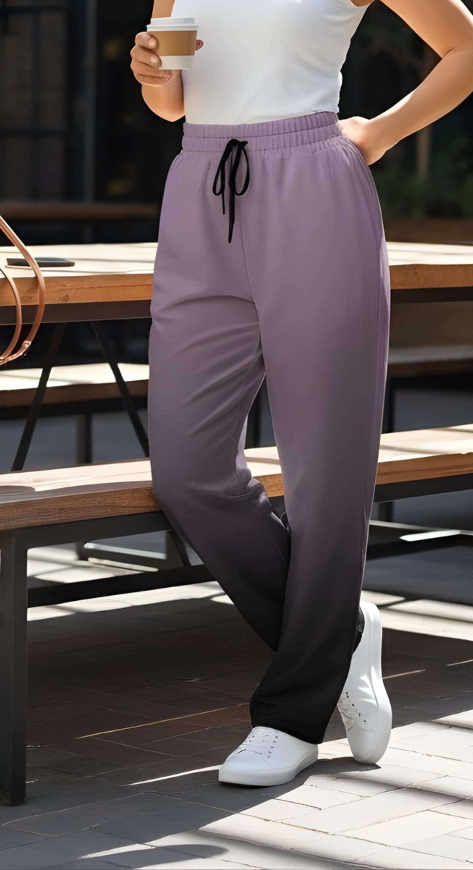 A pair of unisex wide leg joggers that have a ombre pattern starting with a lilac purple at the top then fading to a black at the bottom, the strings are black as well on this pair of pants.