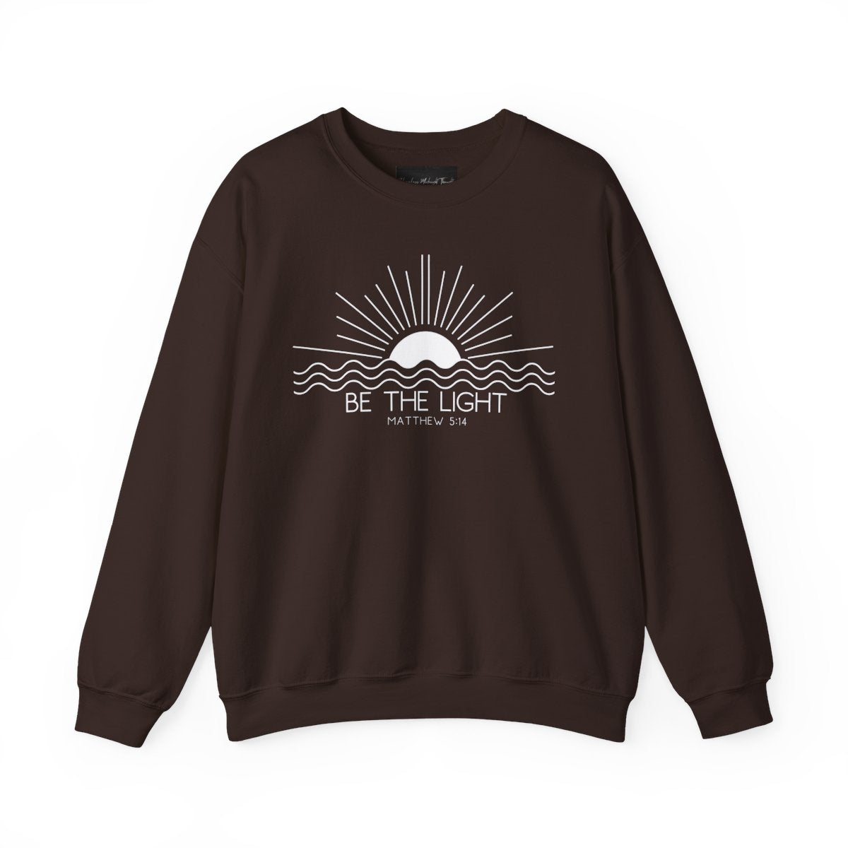 This cozy Christian crewneck sweatshirt features a sunrise over the ocean in the background with the bible verse Be the Light Matthew 5:14 in front of the image.