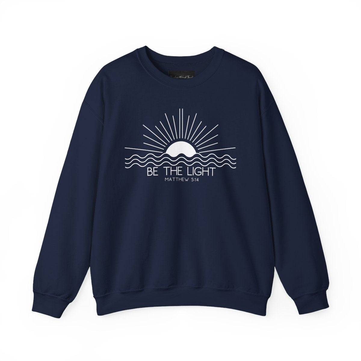 This cozy Christian crewneck sweatshirt features a sunrise over the ocean in the background with the bible verse Be the Light Matthew 5:14 in front of the image.
