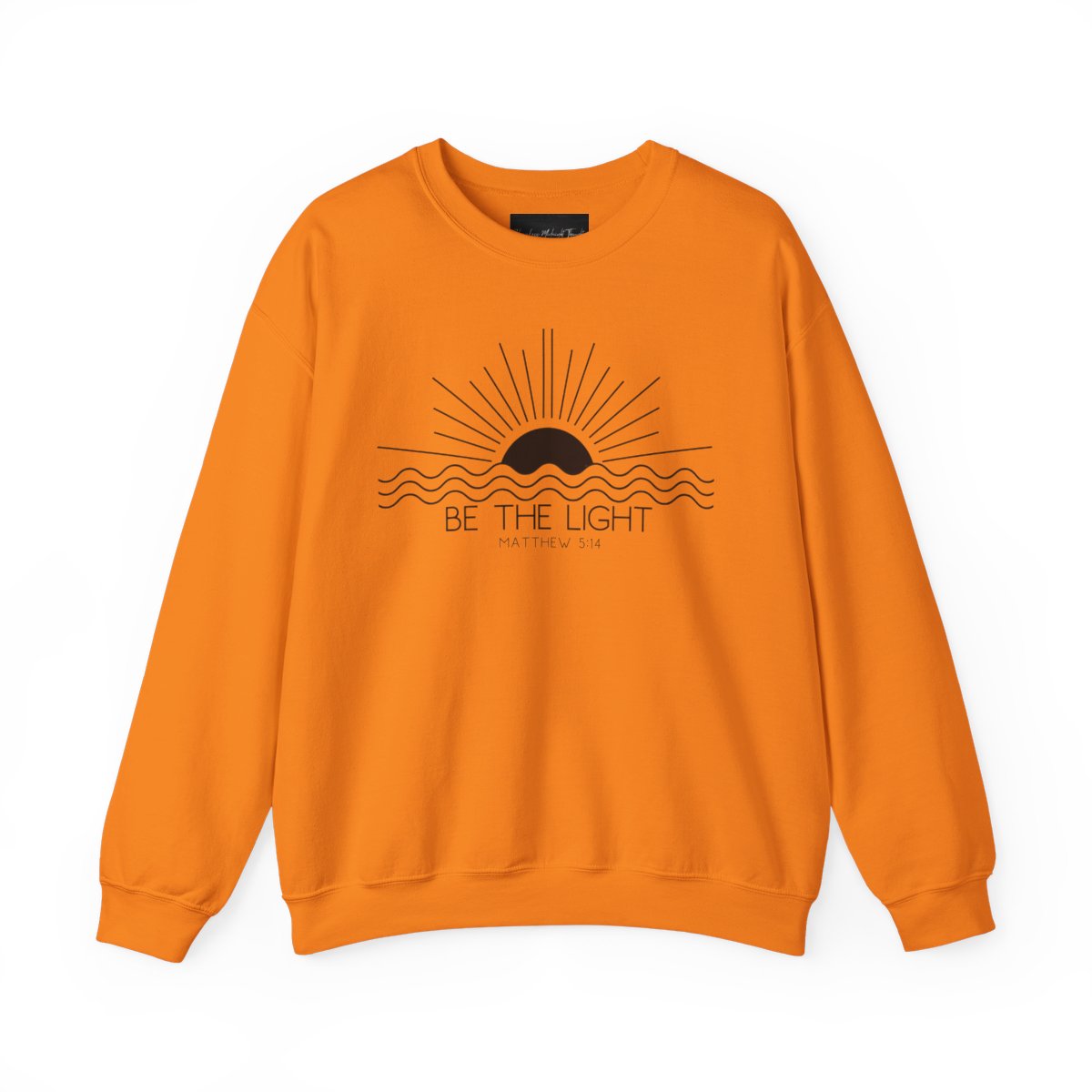 This cozy Christian crewneck sweatshirt features a sunrise over the ocean in the background with the bible verse Be the Light Matthew 5:14 in front of the image.
