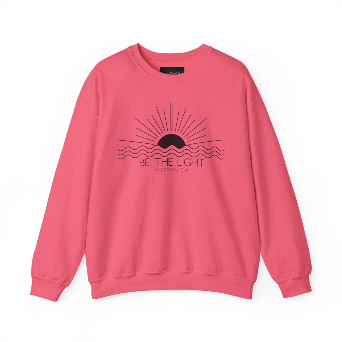 This cozy Christian crewneck sweatshirt features a sunrise over the ocean in the background with the bible verse Be the Light Matthew 5:14 in front of the image.