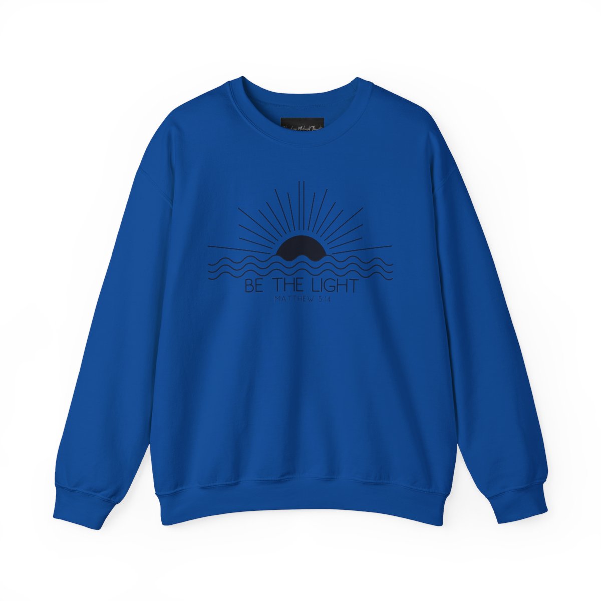 This cozy Christian crewneck sweatshirt features a sunrise over the ocean in the background with the bible verse Be the Light Matthew 5:14 in front of the image.