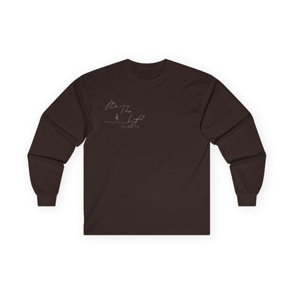 This Christian unisex Long Sleeve t-shirt features the words Be The Light Matthew 5:14 in a simple cursive font with an image of a line drawing of a candle next to the word light.