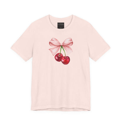 On the front of this custom women's short sleeve shirt is an image of a pair of cherries hanging from a stem with a pink bow on the top of them.