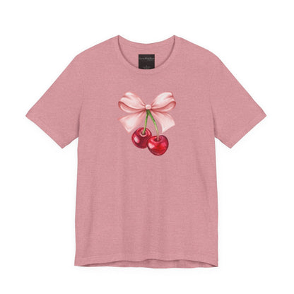 On the front of this custom women's short sleeve shirt is an image of a pair of cherries hanging from a stem with a pink bow on the top of them.