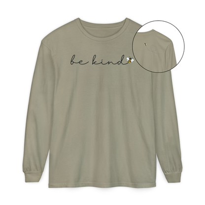 On the front of this custom unisex long sleeve shirt are the words be kind in a simple cursive font, with a bumble bee on the right side of the letter kind, on the back right shoulder there is an image of a bumble bee flying and leaving a trail behind it in the shape of a heart.