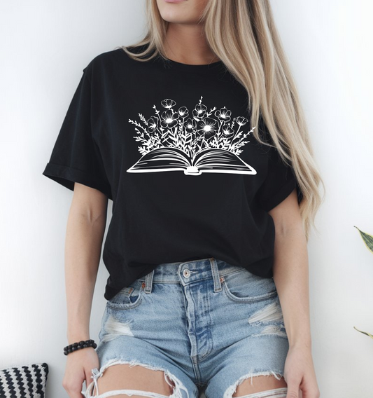 On the front of this custom women's book lover shirt is a image of a book with it opened in the middle, there are a bunch of wildflowers coming out of the center of the book.