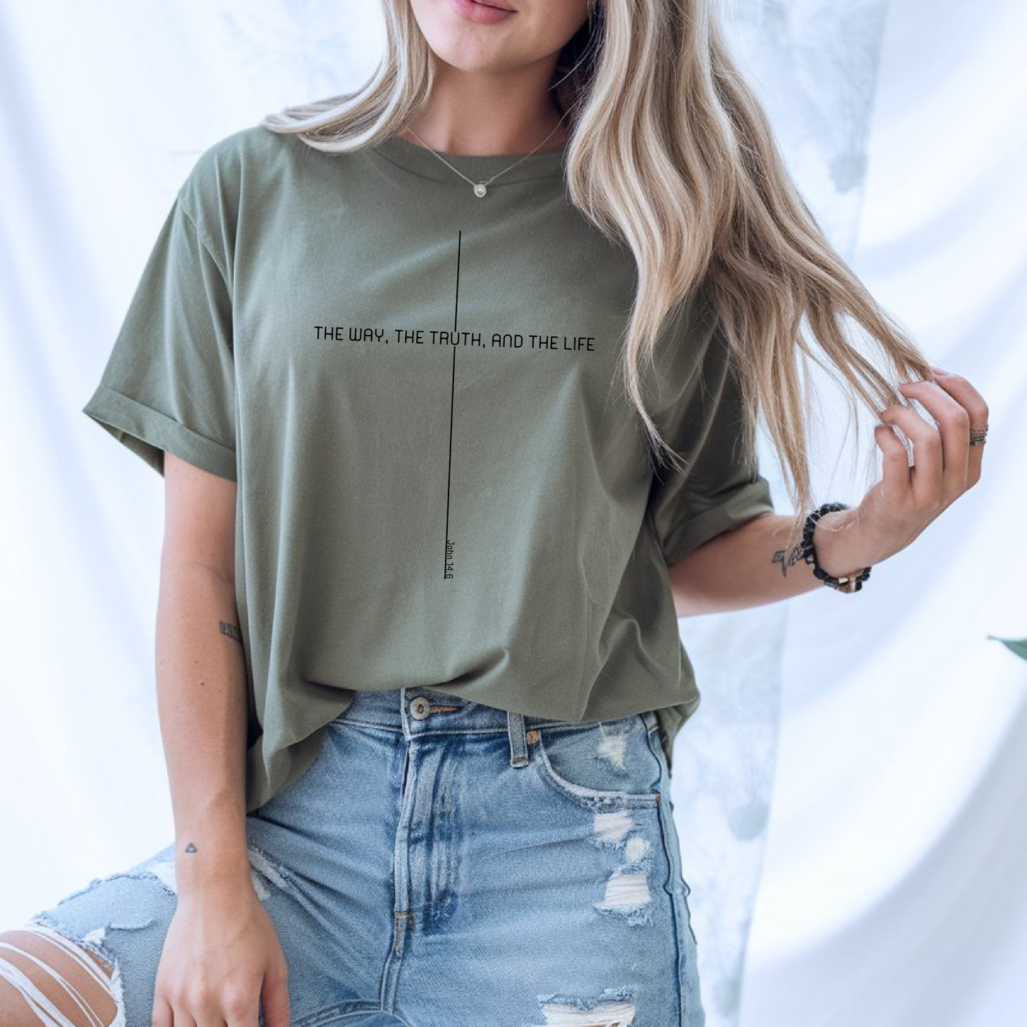 On the front of this custom faith inspired handmade t-shirt is a cross with the bible verse The Way, The Truth, and The Life John 14:6 in a modern font.