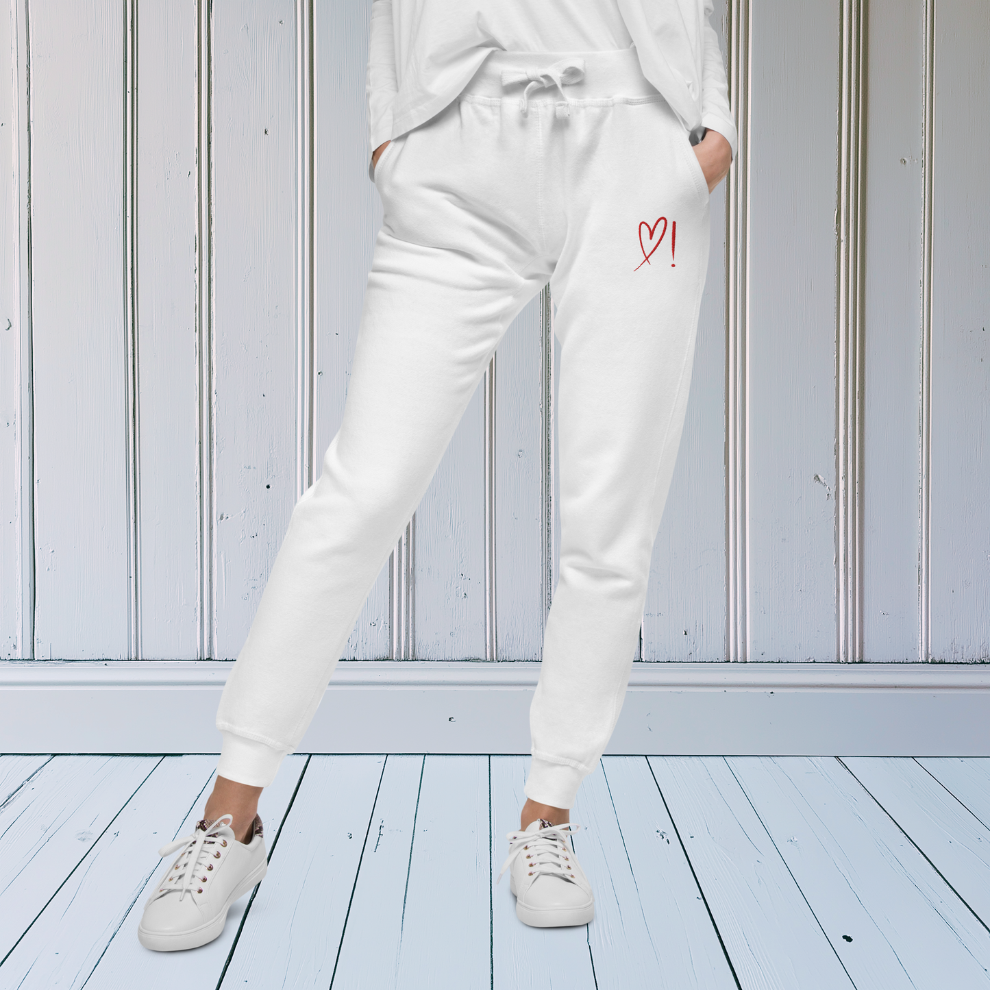 A pair of super soft ankle length unisex sweatpants, there are two pockets on the front and one pocket on the back right. There is a red heart with an exclamation point next to it embroidered on the front left pocket.