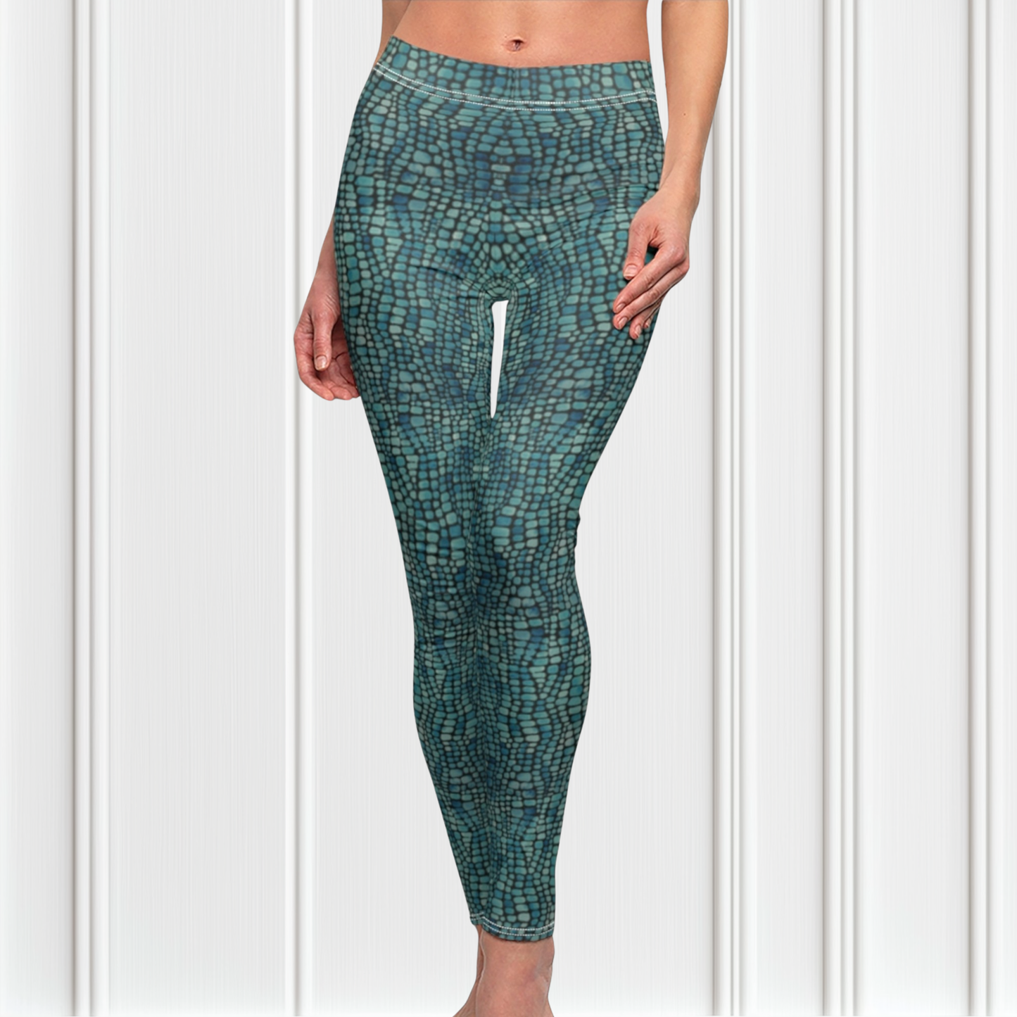 A pair of custom handmade high waisted women's leggings that have a emerald green and turquoise colored snake scale pattern all over the pants.