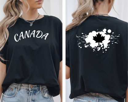 On the front of this custom short sleeve shirt is the word Canada in large letters across the chest, on the back of the shirt in between the shoulder blades is a large paint splatter with a maple leaf in the middle.