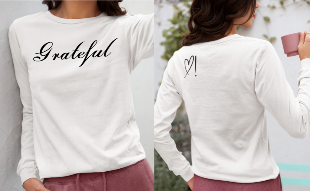 On the front of this custom long sleeve t-shirt in cursive writing is the word grateful on the upper chest, on the back left shoulder blade is an image of a heart with an exclamation mark next to it.