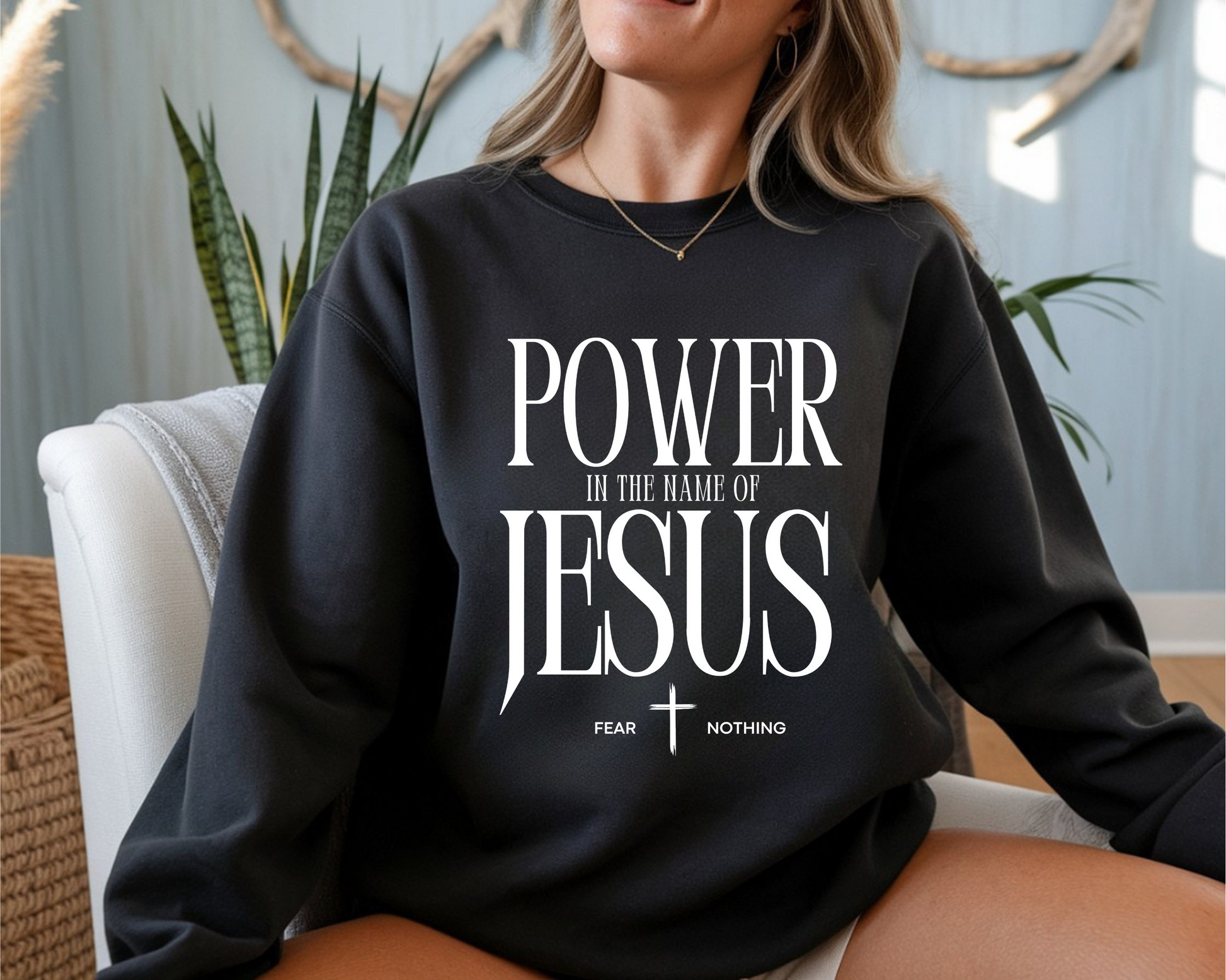 On the front of this Christian pullover sweatshirt it says Power In The Name Of Jesus with a Jesus cross underneath it, on either side of the cross are the words Fear and Nothing.
