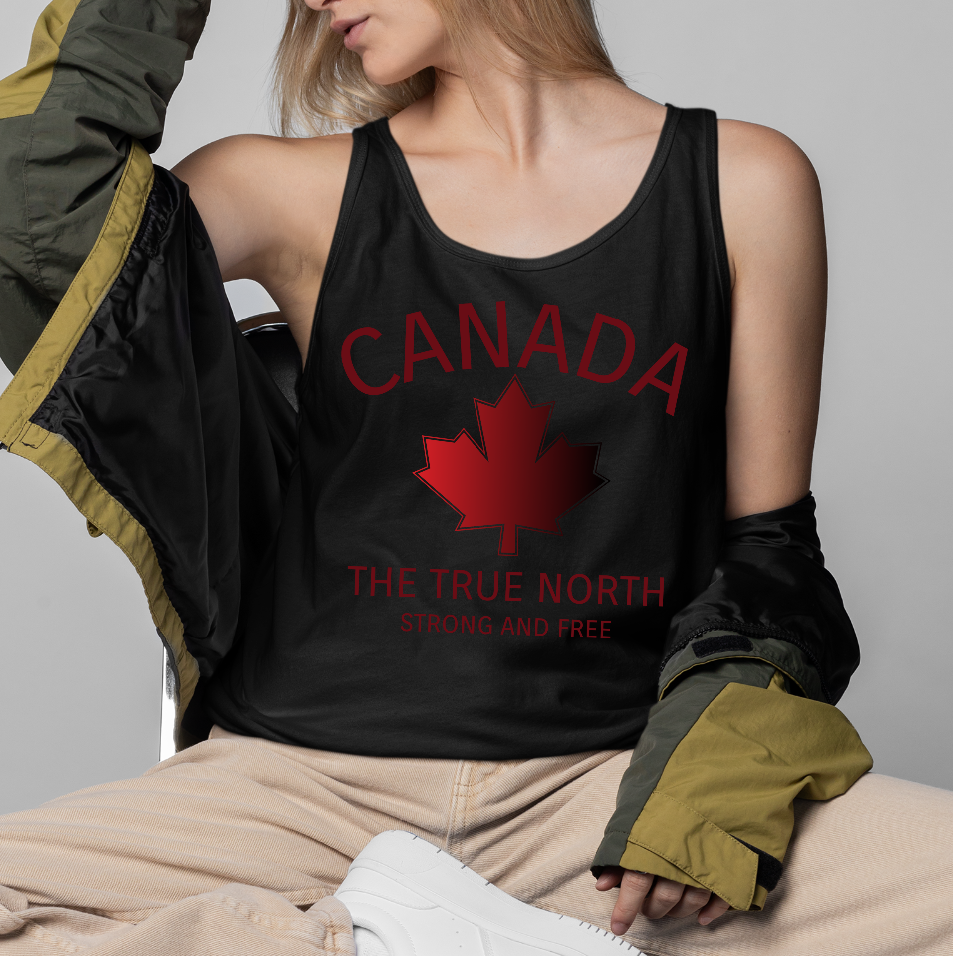 This custom unisex tank top has the word Canada in large block letters in a half circle on the top with a maple leaf underneath that, then under the the maple leaf are the words The True North Strong And Free in the same font, everything is a bright red color like the Canadian flag.