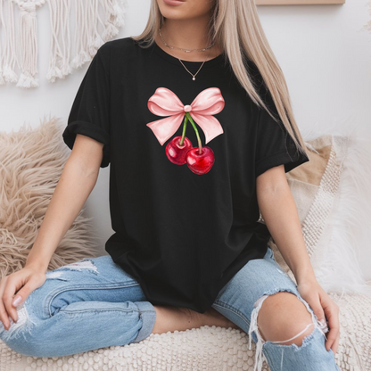 On the front of this custom women's short sleeve shirt is an image of a pair of cherries hanging from a stem with a pink bow on the top of them.