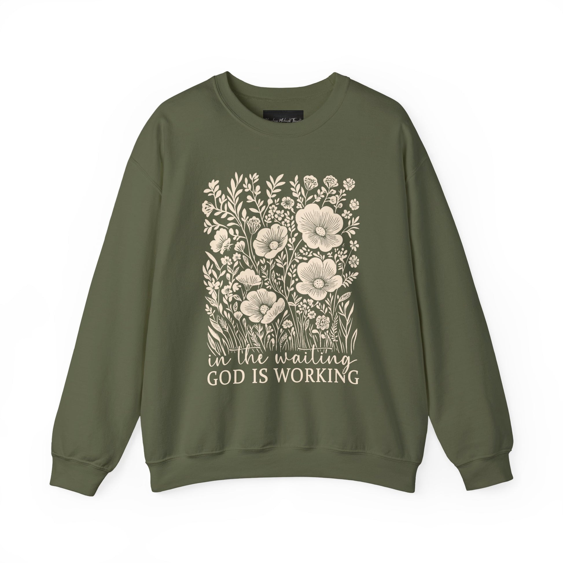 On the front of this custom women's Christian pullover sweatshirt are a bunch of wildflowers with the words in the waiting God is working underneath the flowers.