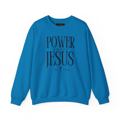 On the front of this Christian pullover sweatshirt it says Power In The Name Of Jesus with a Jesus cross underneath it, on either side of the cross are the words Fear and Nothing.